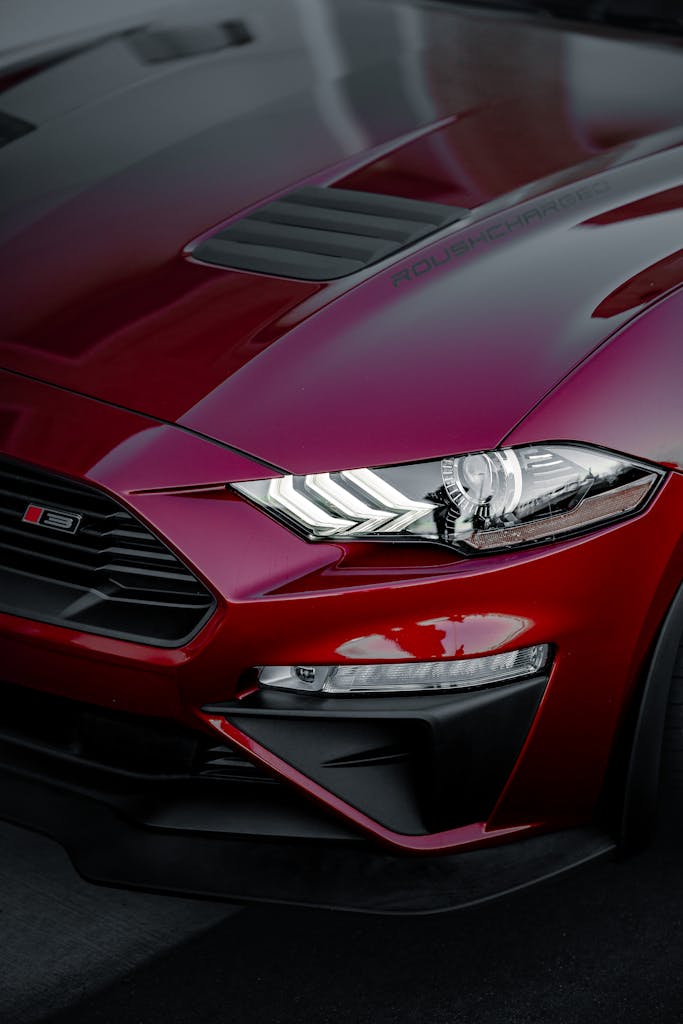 Close-up of a sleek red sports car with modern, angular design elements and a vibrant finish.